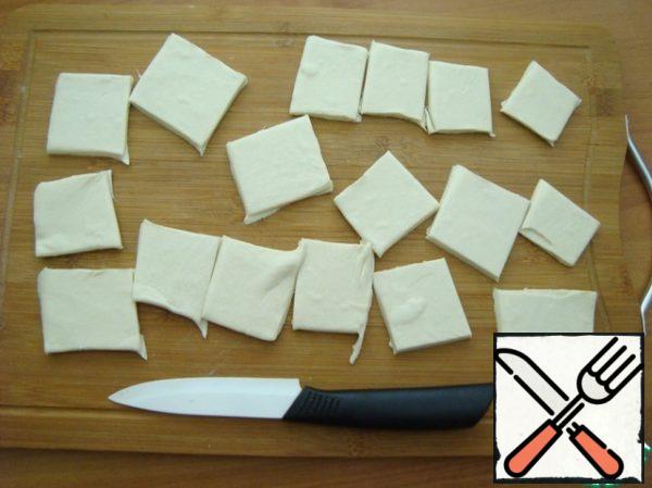 Remove the dough from the refrigerator and let it defrost a little. Preheat the oven to t-180 C. Cut the dough into squares. I cut it arbitrarily. While the oven is warming up, we quickly do the dough. We spread the pieces of dough on a baking sheet covered with baking paper or, like me, on a non-stick mold.

