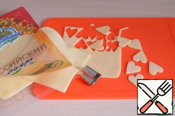 Using cookie cutters, cut out the hearts from the finished slices of cheese.
