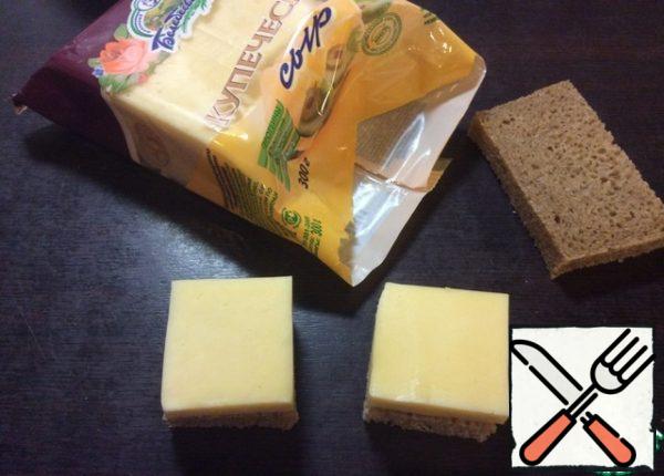 Cut off the crust from a slice of bread. Put a piece of cheese on a slice of bread, cut it to the size of the slice and cut each slice of bread into 4 parts. Pierce a piece of sausage along the edge, thread an olive and pierce the opposite edge of the salami. Insert a toothpick into the center of a piece of cheese with bread.
