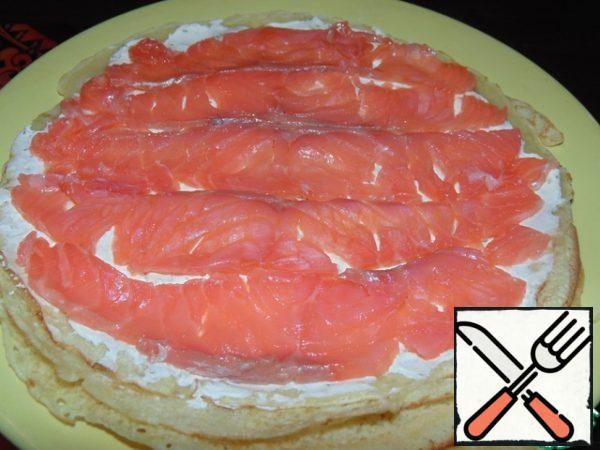The fish is thinly sliced and spread on a pancake with cheese.
