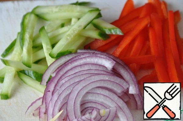 Vegetables wash, clean. Cut the cucumber and Bulgarian red pepper into thin strips, and the red onion into thin half rings.
