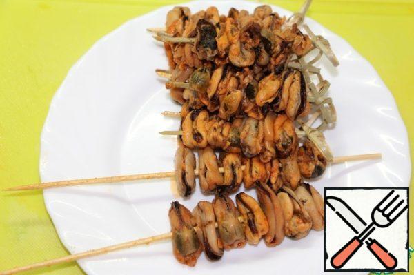 String mussels on wooden skewers.
