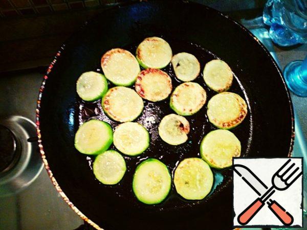 In a frying pan, heat the vegetable oil and fry the rings of courgettes on both sides, salting. Remove when the zucchini will become brown spots.