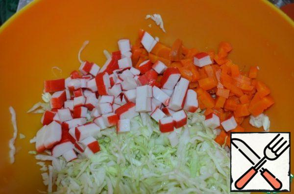 Cut carrots and crab sticks into cubes.
Add to the cabbage.