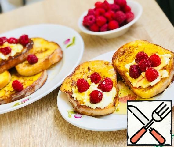 Fry the bread in butter, 1-2 minutes on each side, until appetizing Golden color.
French toast served with cottage cheese and raspberries watering honey.