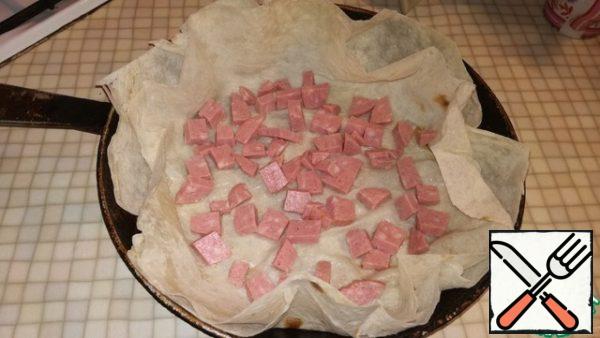 Sausage cut into medium-sized squares and spread on pita bread.