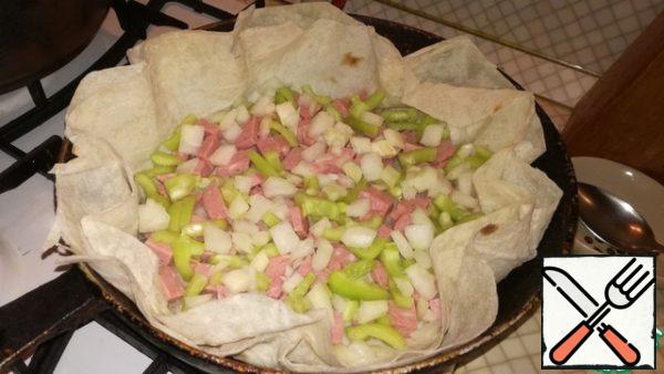 Wash the bell pepper and cut into small pieces, add to the sausage. Finely chop the onion and add to the rest of the ingredients.
