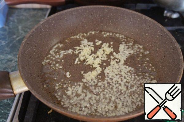 Garlic peel and finely chop with a knife. In a frying pan, heat all olive oil and fry garlic on it for 2-3 minutes.