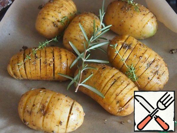 Pan or form for baking lay a paper for baking, put the potatoes, brush with the remnants of the sauce. If there are fresh rosemary and thyme, spread the sprigs on the potatoes.