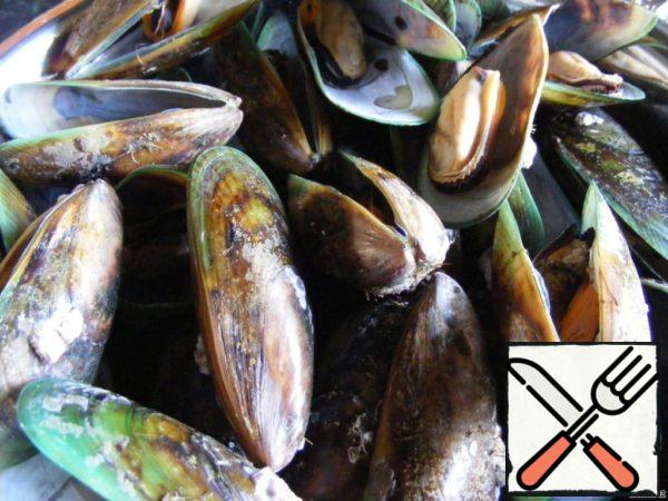 Rinse the mussels under running water. It is better to throw away open and damaged shells.
Bring the water to a boil in a large saucepan. Put the mussels in a saucepan, cover and cook for 5-6 minutes.