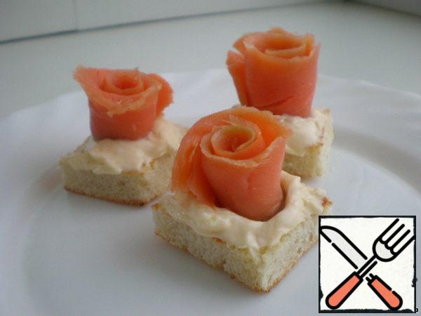 On our toasted canapés generously apply cream cheese. Fish twist the roll and put on the canapes, slightly drowning in cheese, do not need any toothpicks for fastening, everything will hold as it should.