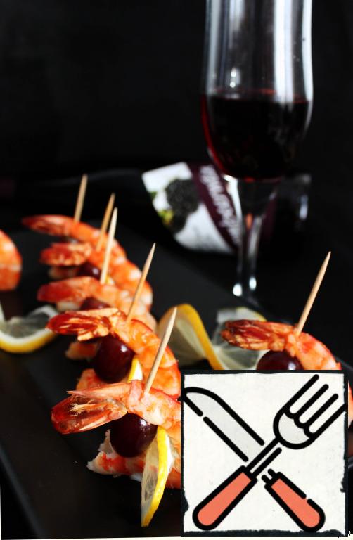 Put on shrimp and grape berries on skewers or long toothpicks, decorate with lemon slices. It is desirable to take grapes with a light acidity. Or just with a bright taste, even sweet, lemon will complement the missing acidity.