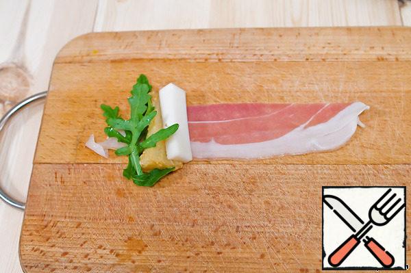 One piece of jamon put a piece of pear, a slice of cheese and a few leaves of lettuce. Roll into a roll and pierce with a skewer. This snack can be served immediately.