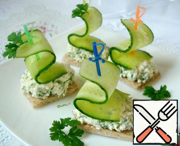 For each bread, spread the cheese mass. Strung on a skewer a piece of cucumber and decorate canapés.