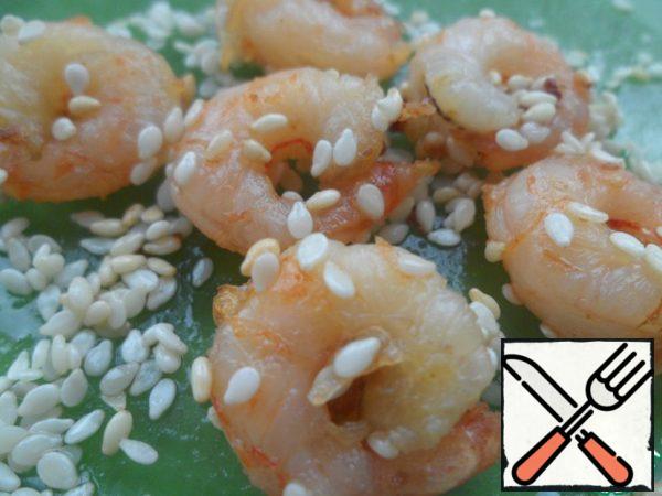 Fry shrimps in oil with salt and pepper, roll in sesame seeds. Chop the calamari-crab roll, slice 1.5 cm thick. On skewer strung a circle of rolls and put on the top of the shrimp.
Sprinkle everything with sesame and lime zest.