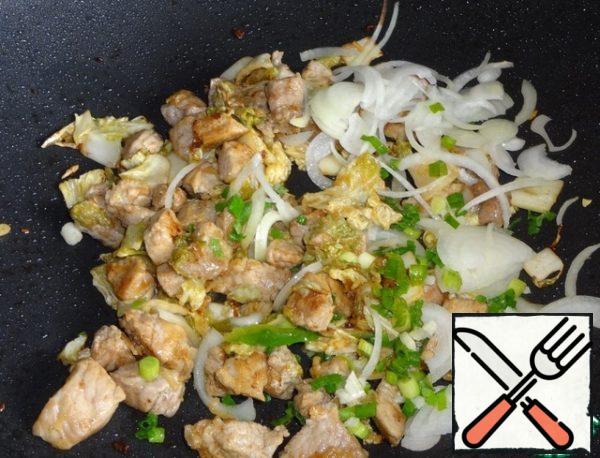 Warm up the pan with a thick bottom, put vegetable oil and start frying pork and cabbage kimchi. I used the wok pan.
Fry the meat for about 10 minutes. Then add the green and onions, fry for another 5 minutes.