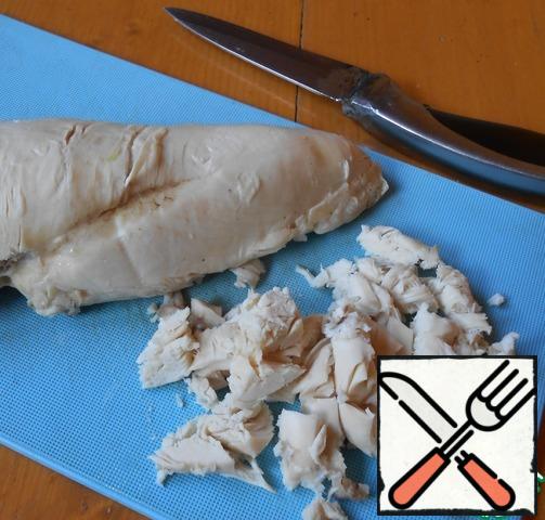 Boil chicken fillet, cool and cut.