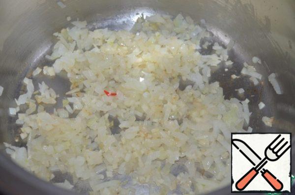 Pour olive oil into a saucepan with a thick bottom, fry onion and garlic on it until transparent.
