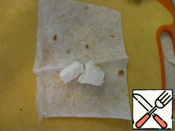 Pita bread cut into small pieces. On one slice put Adygei cheese and roll into tube.