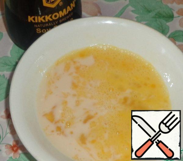 Prepare the filling. Beat the egg with a fork and mix with melted milk and soy sauce.
