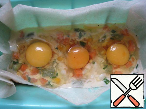 Put half of the mixture into a greased rectangular shape. We cover the form with paper, because the quality of my form leaves much to be desired.
Carefully break 3 eggs into the center.
