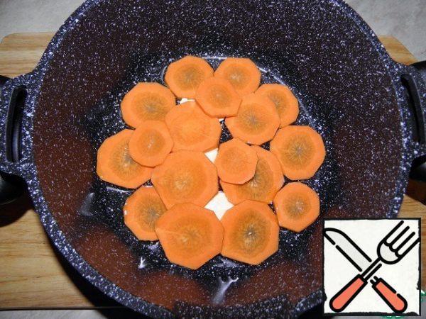 At the bottom of the pan (thick bottom) add butter and vegetable oil, put the sliced carrot mugs (salt, pepper top, to taste).