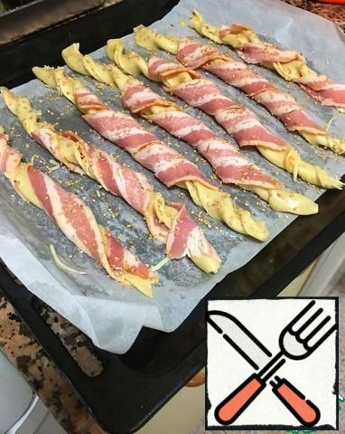 In a slice of bacon (I have already cut into thin strips) wrap each flagellum. Lightly grease the resulting sticks with egg and sprinkle with spices (for example, rosemary) and sesame seeds and send in a preheated oven for about an 20 minutes.