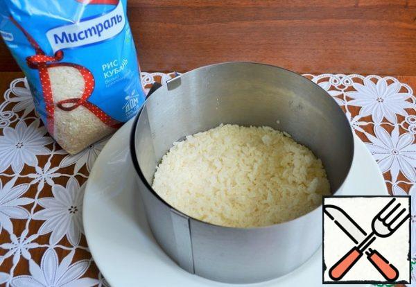 Boil the rice. It is better to do it in advance to cool the rice and a little dry. Mix rice with 2 tablespoons of mayonnaise, salt. Put into a form for the salad or just the first layer.