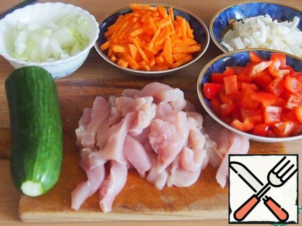 Cut onion and pepper into pieces. Cut the carrots into cubes, the white part of a small leek into rings, and the chicken fillet into thin strips.
