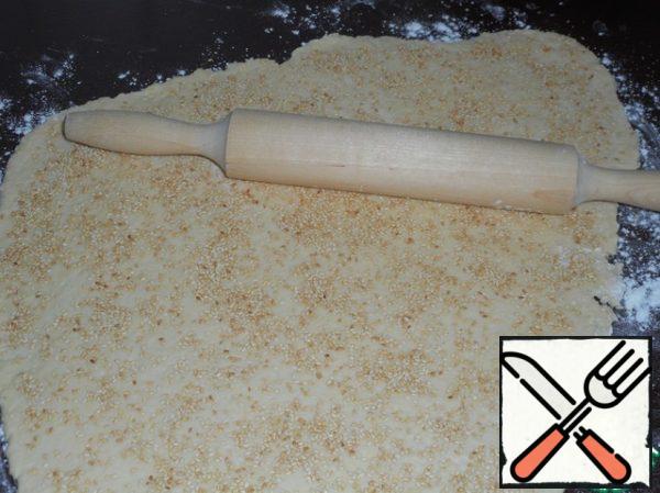 Generously sprinkle the surface of the dough with sesame seeds, rolled with a rolling pin.