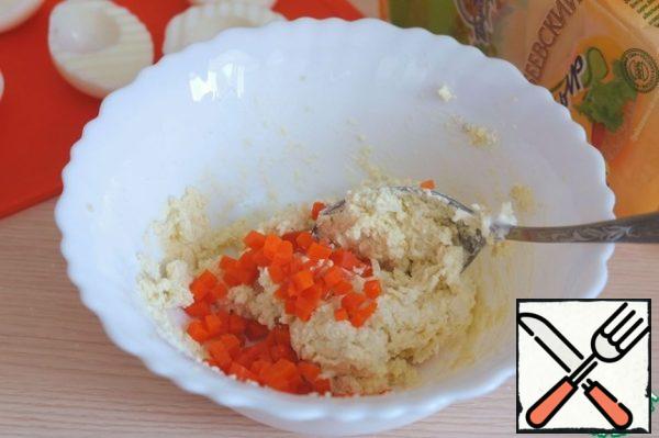 Add some of the chopped carrots to the mixture of grated cheese and egg yolk. Mix well.