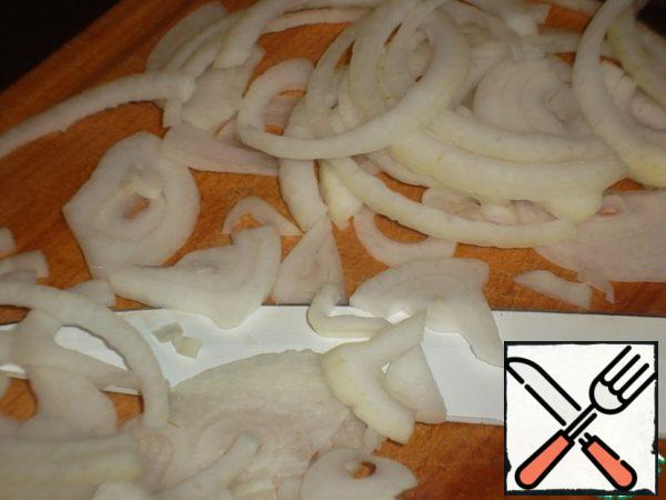 Peel the onion and cut it into thin half rings.
