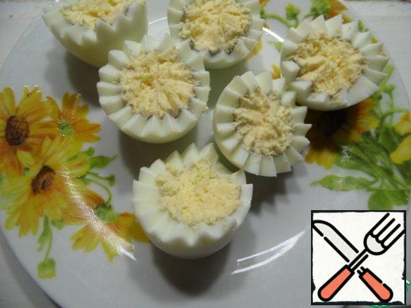 Cut the eggs in half (you can do it figuratively), stir the yolks with a fork.
