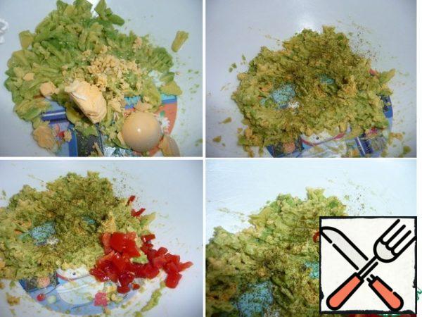 Boil an egg. Peel off the shell. Cut in half lengthwise, remove the yolk and add it to the avocado in a bowl. Mash with a fork. Put the protein aside. Add spices. Finely chop the tomato and chili pepper.
