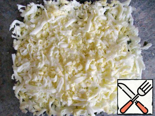 The second layer is three eggs grated on a coarse grater.
