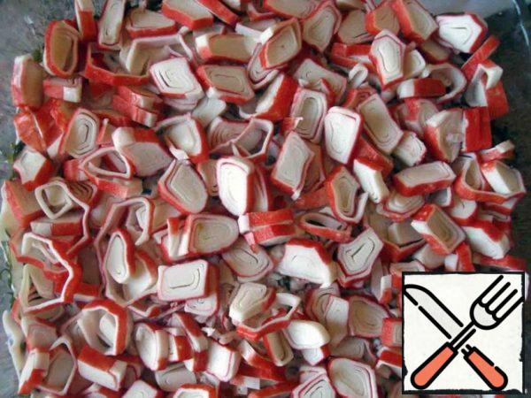 Seventh, crab sticks. They can be finely chopped, you can - on a grater. I unwrapped them too nicely, so I did this.
