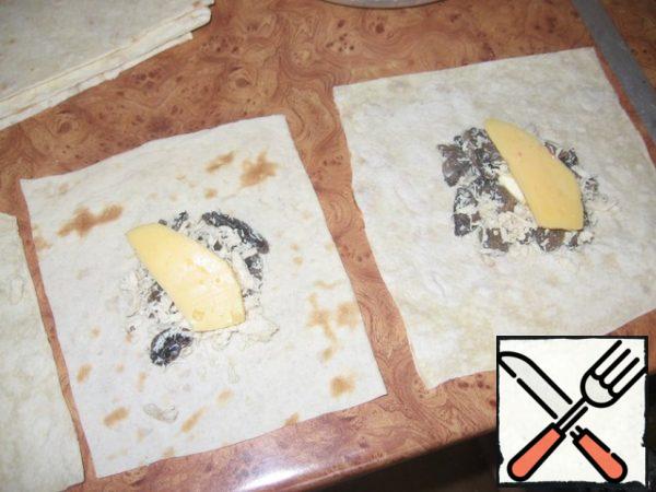 Pita bread is divided into squares, put the filling in the middle, add a little mayonnaise, put a piece of cheese on top. 
