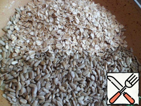Pour whole-grain oat flakes and sunflower seeds into a dry frying pan.

