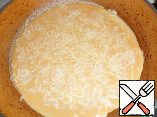 Heat a frying pan with butter, pour the egg mixture, put the grated cheese on top. On a small fire bake an omelet with one hand. Remove the spatula on the Board and roll into a roll, cheese inside.