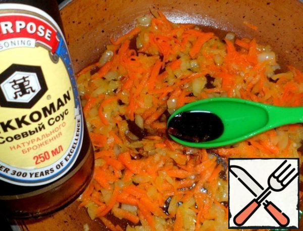 Chop onions finely and fry in a frying pan with heated vegetable oil, add grated carrots, stir and pour soy sauce.