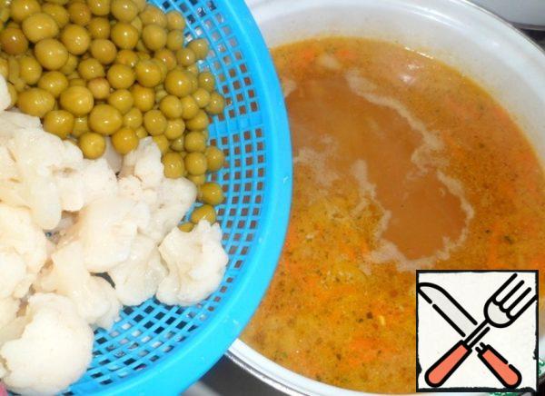 Add cauliflower and green peas. My cauliflower is boiled and frozen. Rinse under running water, thus remove the ice. Canned peas. Return the chicken pieces to the soup. All together boil two or three minutes on low heat. Cover, turn off the heat and let stand for 5-10 minutes.