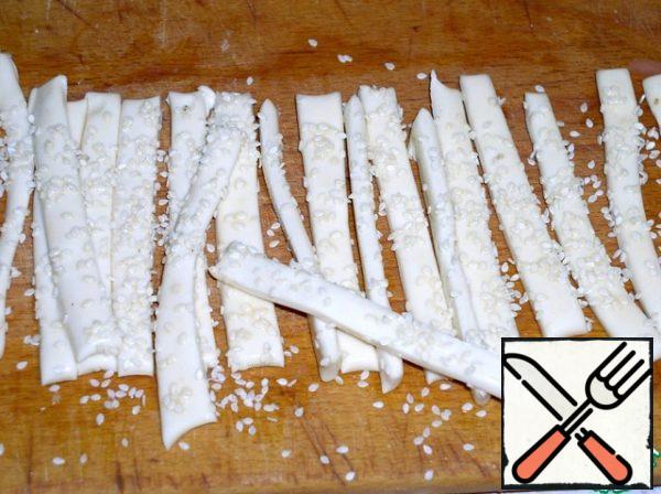 Cut the dough into strips, the thickness of which should not exceed 1 centimeter. Sprinkle the strips with sesame seeds.
