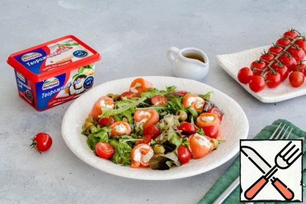 Mix with 1 tablespoon of green salad dressing, spread on plates. Next, lay out the rolls of fish and cheese, put tomatoes and olives on the leaves. Sprinkle with the remaining dressing and serve.