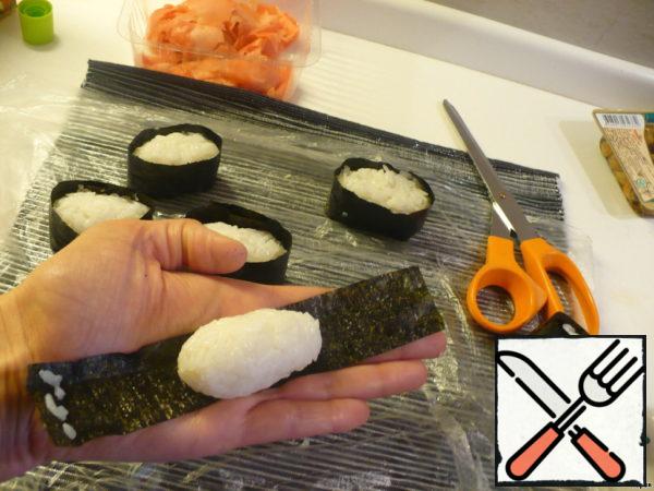 Then put a strip of nori on the hand, on it-rice, on one side of nori-a couple of rice bands to the edges stuck together and wrap the ball of rice in nori.