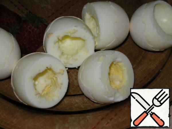 Boil and peel the eggs, as in the photo, cut off the tops, egg yolks and egg white grate to the filling on a fine grater.
