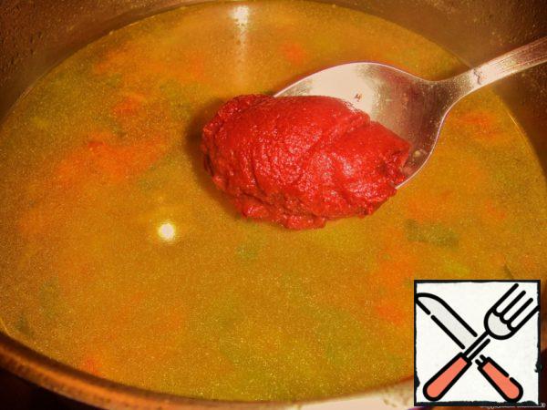 Now for a few seconds remove the pan from the heat and mash vegetables with a potato masher right in the soup. Add tomato paste, finely chopped garlic and chopped ginger root.