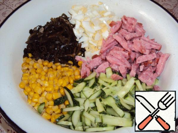 Sausage or ham and cucumber cut into strips, eggs and onions in small cubes. Add sea cabbage, corn.