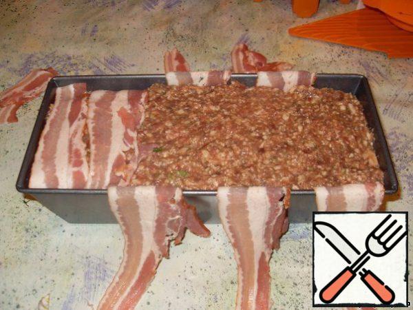 Liver, pork and fat through a meat grinder, add crushed garlic, herbs and spices, stir. Add cognac, very finely chopped onion and egg. Knead.
Sides of the form to layout staggered strips of bacon so that they hung from the edges. Lay on the bottom of the baking paper.