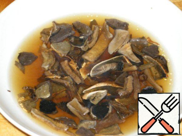 Dry mushrooms soak in boiling water for 10 min., then squeeze, finely chop, mushroom broth is not poured, we still need it.