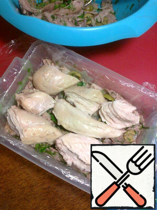 Moisten the mold with water (for a better fit of the film) and cover with food wrap (the edges of the film should hang down). Put the pig skin on the film. Spread the meat mixture over the skin to half. Then I spread a layer of chicken breast, then the meat mixture again.
